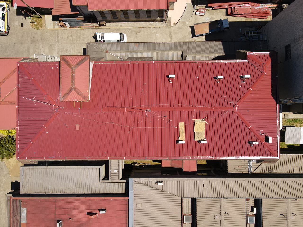 Mastering the First Impression: Your intriguing post title goes here Aerial view showcasing vibrant red metal rooftops in a city, highlighting architectural patterns and urban organization.